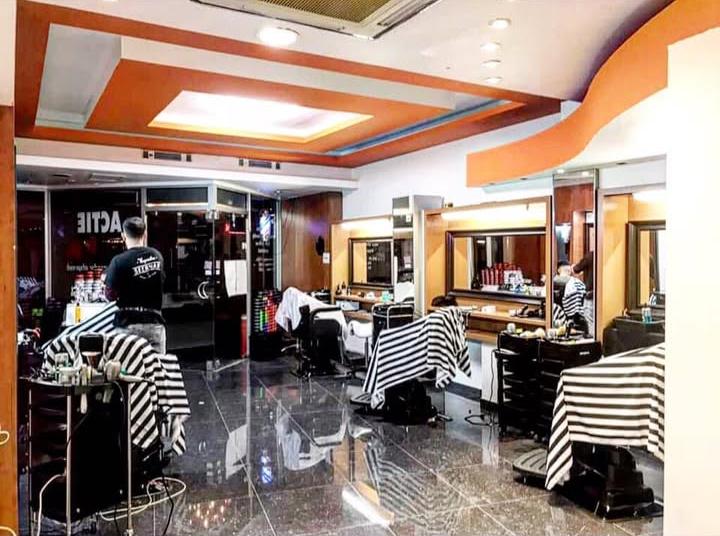Interieur van Kapsalon Seerwan met kappersstoelen, gestreepte capes en spiegels in houten kasten