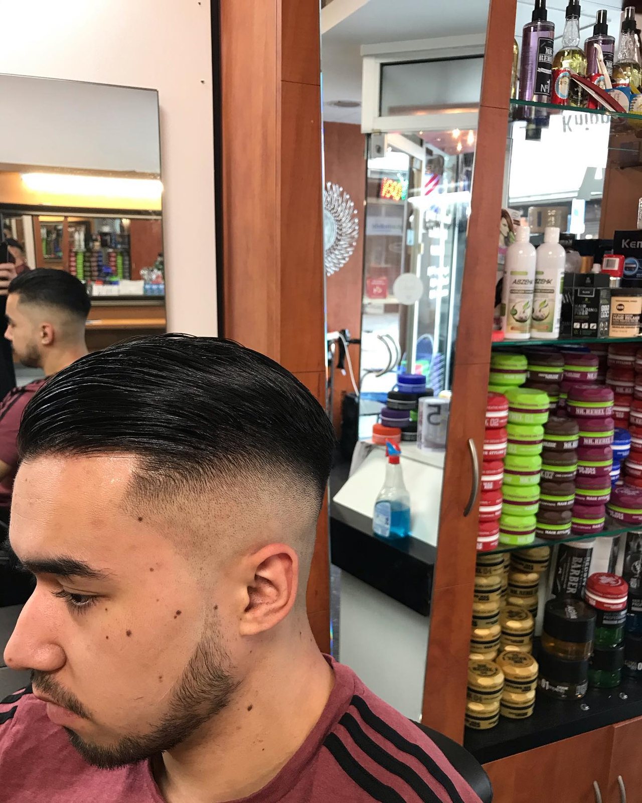Klant met een verse fade en strak getrimde baard voor de productkast
